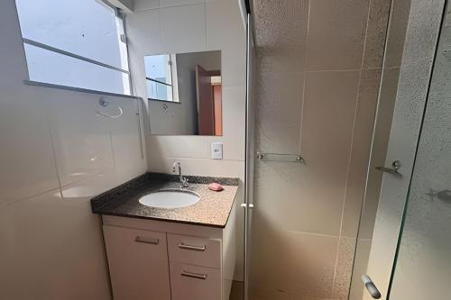 a bathroom with a sink and a mirror and a shower at Vila São José 1 in Ourinhos
