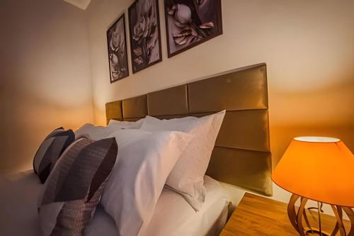 a bedroom with a bed with white pillows and a lamp at Vila São José 1 in Ourinhos