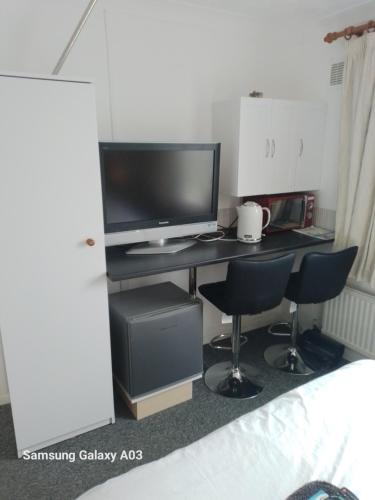 a computer desk with two chairs and a television at Windsor 1 Hunstanton in Kings Lynn