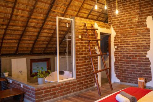 Un baño con una pared de ladrillo con un espejo y una escalera. en Cliff Edge Villa, en Ella