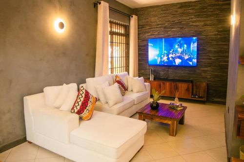 sala de estar con 2 sofás blancos y TV en Safari Homes Tz, en Arusha