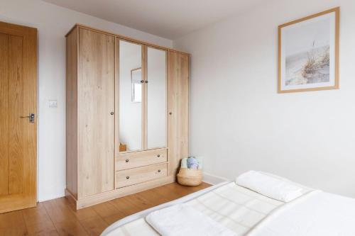a bedroom with a bed and a wooden cabinet at Sunny 1 bedroom apartment, Ocean house, East wittering in East Wittering