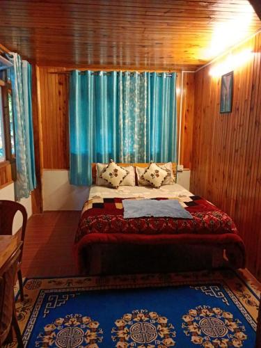 a bedroom with a large bed with blue curtains at Bloomfield Farmhouse 2 in Darjeeling