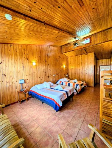 two beds in a large room with wooden walls at Miztli Lodge & Adventure in Monteverde Costa Rica