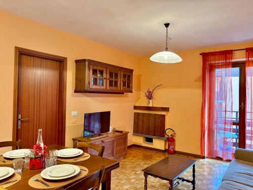 a living room with a table and a television at In Valle - A pochi passi da tutto in Chiesa in Valmalenco