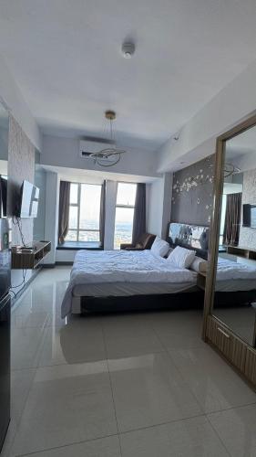a large bedroom with a large bed and a mirror at Luxury Apartemen Anderson Benson PTC By Staycation in Surabaya