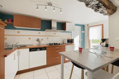 a kitchen with white cabinets and a wooden table at Gite Cours Péan in Châteaugiron