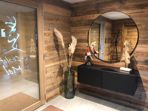 a room with a mirror and a vase with feathers at Chalet Au Chalet de Mel très récent in La Bresse