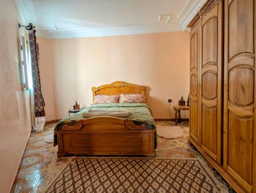 a bedroom with a wooden bed and a dresser at chambre dans un havre de paix creatif in Essaouira
