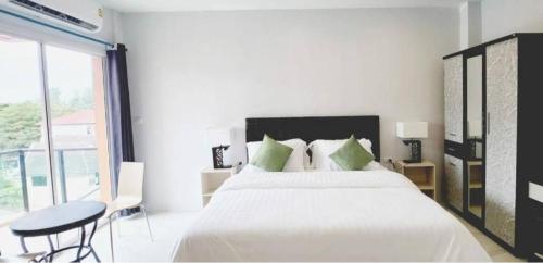 a white bedroom with a large bed and a table at PR ROOM FOR RENT in Kamala Beach