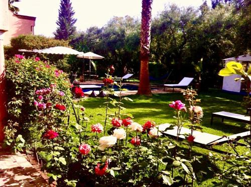 a garden with flowers and a table and benches at Villa Aalama in Marrakech