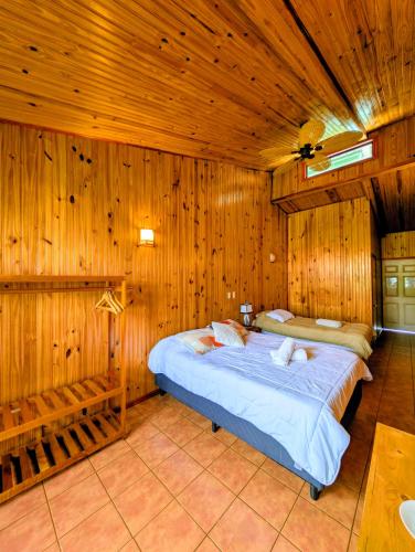 a bedroom with two beds in a room with wooden walls at Miztli Lodge & Adventure in Monteverde Costa Rica