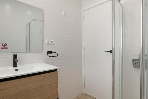 een witte badkamer met een wastafel en een douche bij Casa Azul in Conil de la Frontera