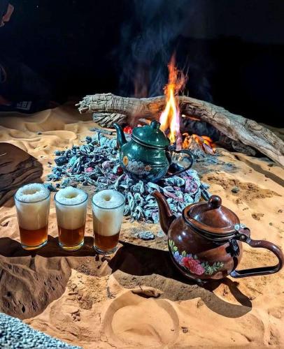 a table with a tea pot and three glasses of beer at Casa de las Estrellas in Mhamid