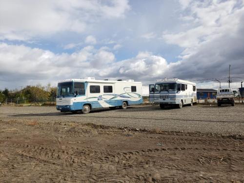 two buses parked next to each other in a parking lot at Patagonia RV stop in Puerto Natales