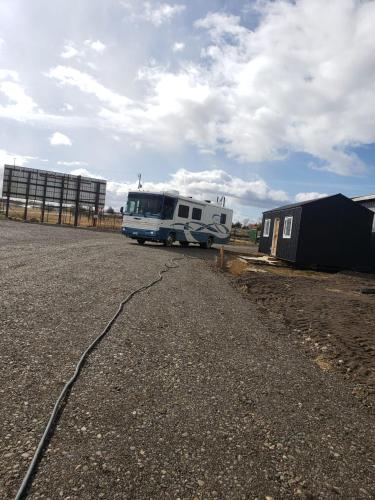 a bus parked in a parking lot with a trailer at Patagonia RV stop in Puerto Natales