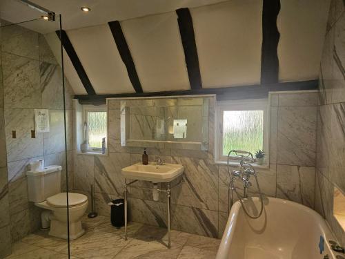 a bathroom with a sink and a toilet and a tub at Plum Pudding Barn in Kent