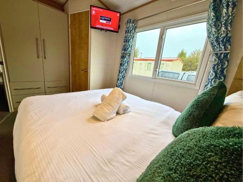 a bedroom with a white bed with a window at Private Hot Tub & Spacious Decking Area in Northumberland, Dog-Friendly, Free Golf Access in Swarland
