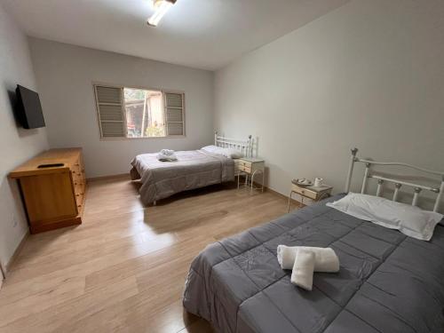 een slaapkamer met twee bedden en een televisie bij Keller Reservas in Resende