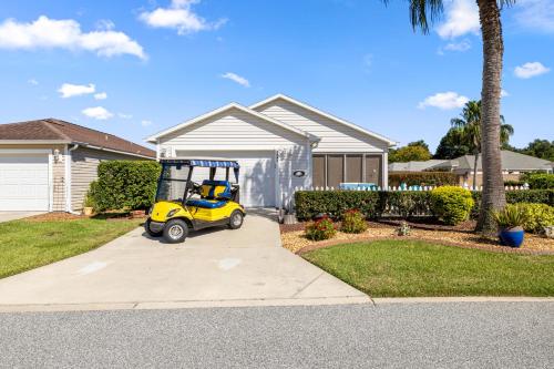 a yellow golf cart parked in front of a house at Sunnyside Escape in The Villages With Golf Cart & BBQ in The Villages