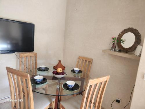 a dining room with a glass table with chairs and a tv at Atlas golf in Marrakech