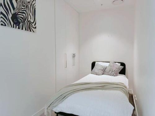 Habitación blanca con 1 cama con 2 almohadas en Bright Airy Stay Apartment, en Sídney