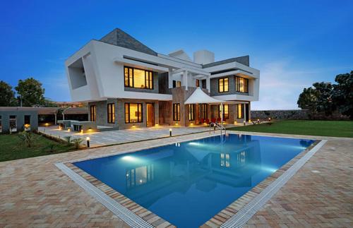 una casa grande con piscina frente a ella en Chacha Villa, en Ābu Road
