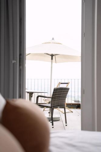 a chair with an umbrella sitting on a balcony at Hotel & Restaurant Nollen in Hosenruck