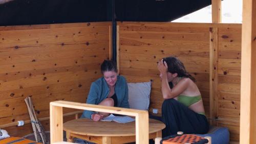 two women sitting on a bed in a wooden room at Fu SPACE in Tamraght Ouzdar