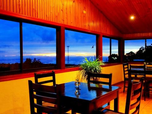 a dining room with a table and chairs and windows at Miztli Lodge & Adventure in Monteverde Costa Rica