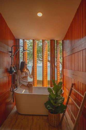 a woman sitting in a bath tub in a room with a window at Bamboo Seaview Koh Larn Second Floor - 2nd Floor in Ko Sak