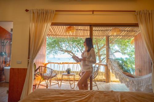 a woman standing in a bedroom with a view of the ocean at Bamboo Seaview Koh Larn Second Floor - 2nd Floor in Ko Sak