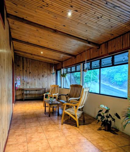 two chairs and a table in a room with windows at Miztli Lodge & Adventure in Monteverde Costa Rica