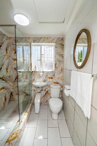 a bathroom with a toilet and a sink and a mirror at Self Contained 2 bed Room Condo in Parow