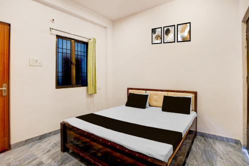 a bedroom with a bed with white walls and a window at Hotel O Ujala Guest House in Varanasi