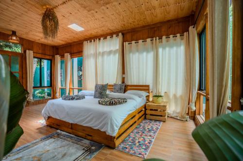 a bedroom with a bed in a room with windows at Mango Eco Cabin by Banana Farm in Nkoanrua