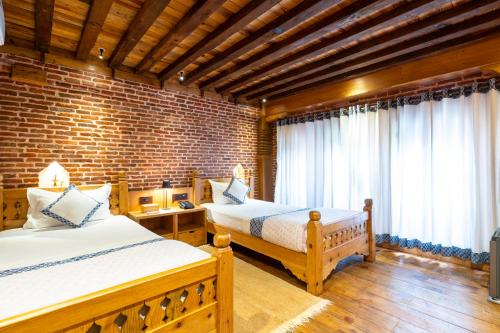 a bedroom with two beds and a brick wall at Sulimha Durbar in Pātan