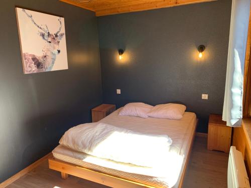 a small bedroom with a bed with white sheets at Chalet Gaby - chalet atypique avec SPA in Xonrupt-Longemer