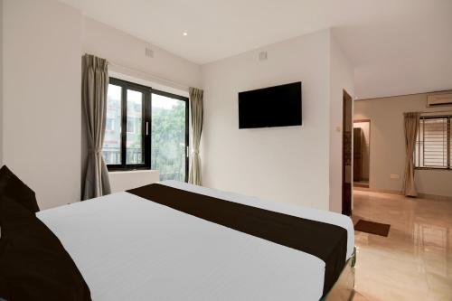 a bedroom with a white bed and a television at Hotel O Avigna Premium in Bhubaneshwar