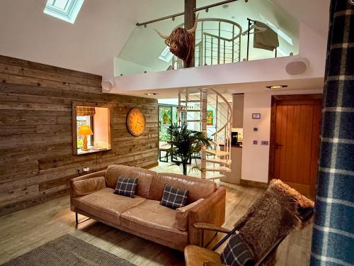 a living room with a brown couch and a wooden wall at Balloan Cottage Cowshed in Inverness