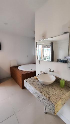 a bathroom with a sink and a mirror and a tub at Essência do Sol Pousada in Florianópolis
