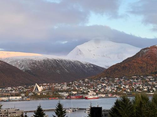 a city with a snowy mountain in the background at Charming and spacious wooden house right in the city centre in Tromsø