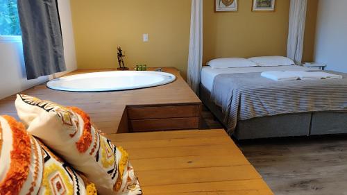 a bathroom with a tub and a bed and a bed and a sink at Essência do Sol Pousada in Florianópolis