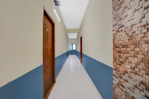 a hallway with blue and white walls and a brick wall at Hotel O SLV BOARDING & LODGING in Kammasandra