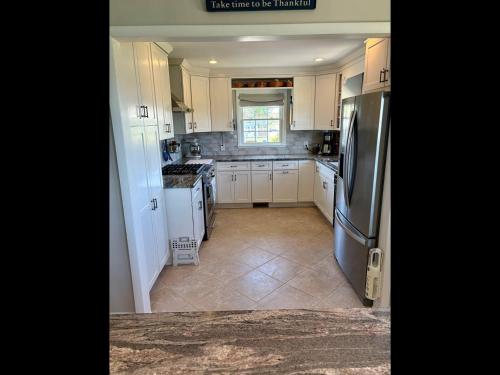 a kitchen with white cabinets and a stainless steel refrigerator at Island Time home in Holden Beach