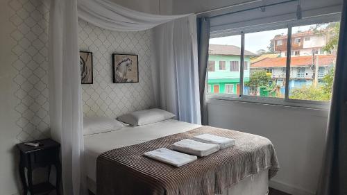 a bedroom with a bed with three towels on it at Essência do Sol Pousada in Florianópolis