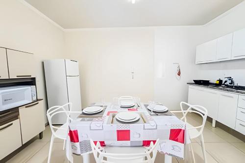a white kitchen with a table and white appliances at Vila São José 2 in Ourinhos
