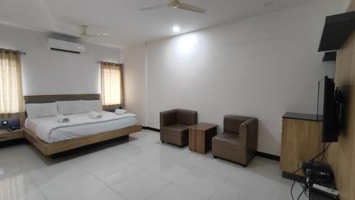 a bedroom with a bed and a tv and a chair at Embassy Grand in Jāmb