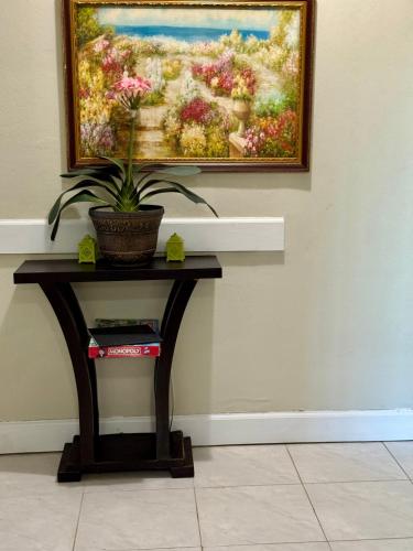 a painting hanging on a wall with a table with a plant at Breezy Castle Villa with private pool overlooking the Sea and Blue Mountains in Port Maria