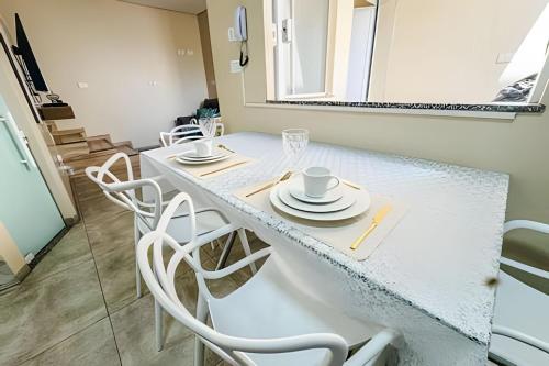 a white table with white chairs and a mirror at Lindo sobrado no centro, ar cond e vaga in Ourinhos